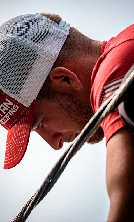 Close-up of a Titan Roofing crew member in a branded cap, working