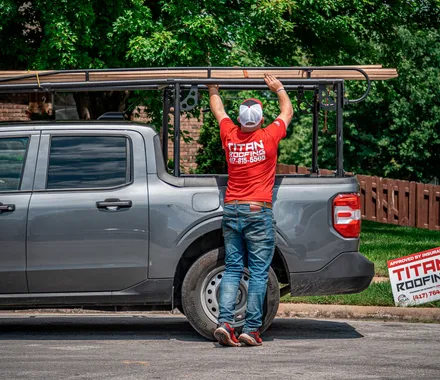A Titan Roofing crew member loading material onto a truck rack