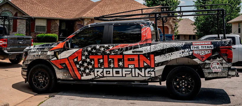 A wrapped Titan Roofing truck parked outside a home