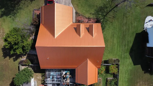 Aerial view of a home with a new copper-toned standing-seam metal roof