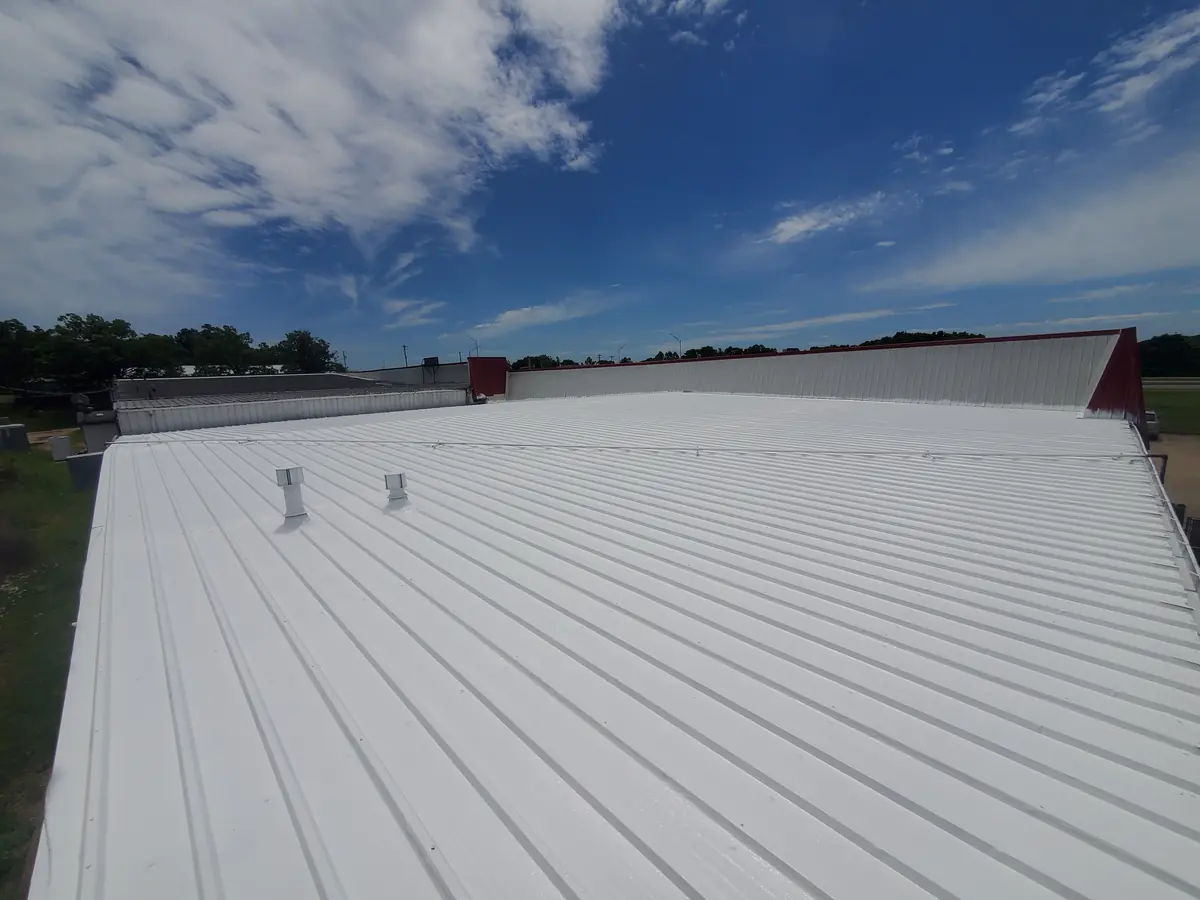 White coated metal roof on a commercial building under a blue sky