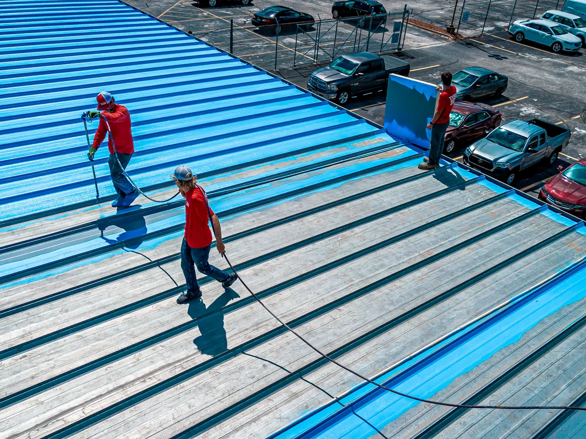 Titan crew applying a blue roof coating to a commercial metal roof