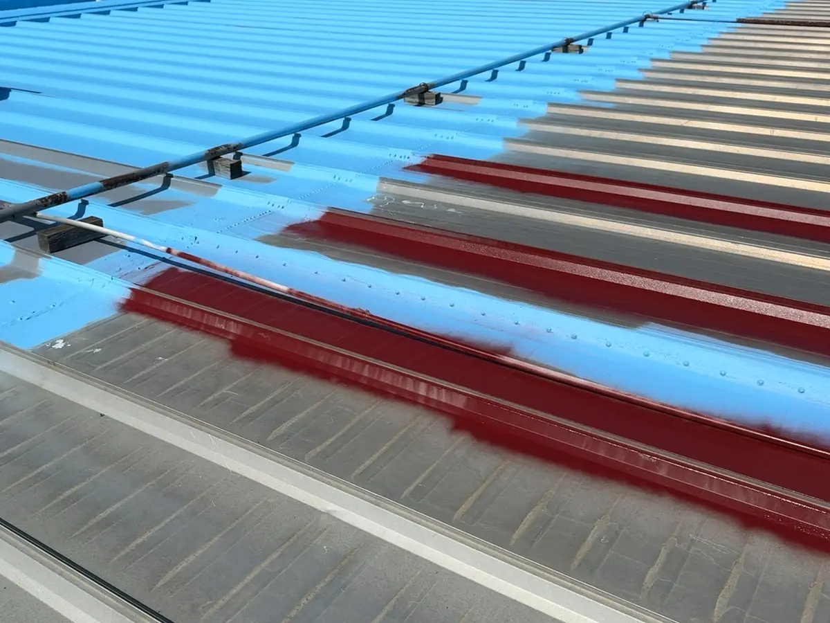 Blue roof coating going on over an older metal roof