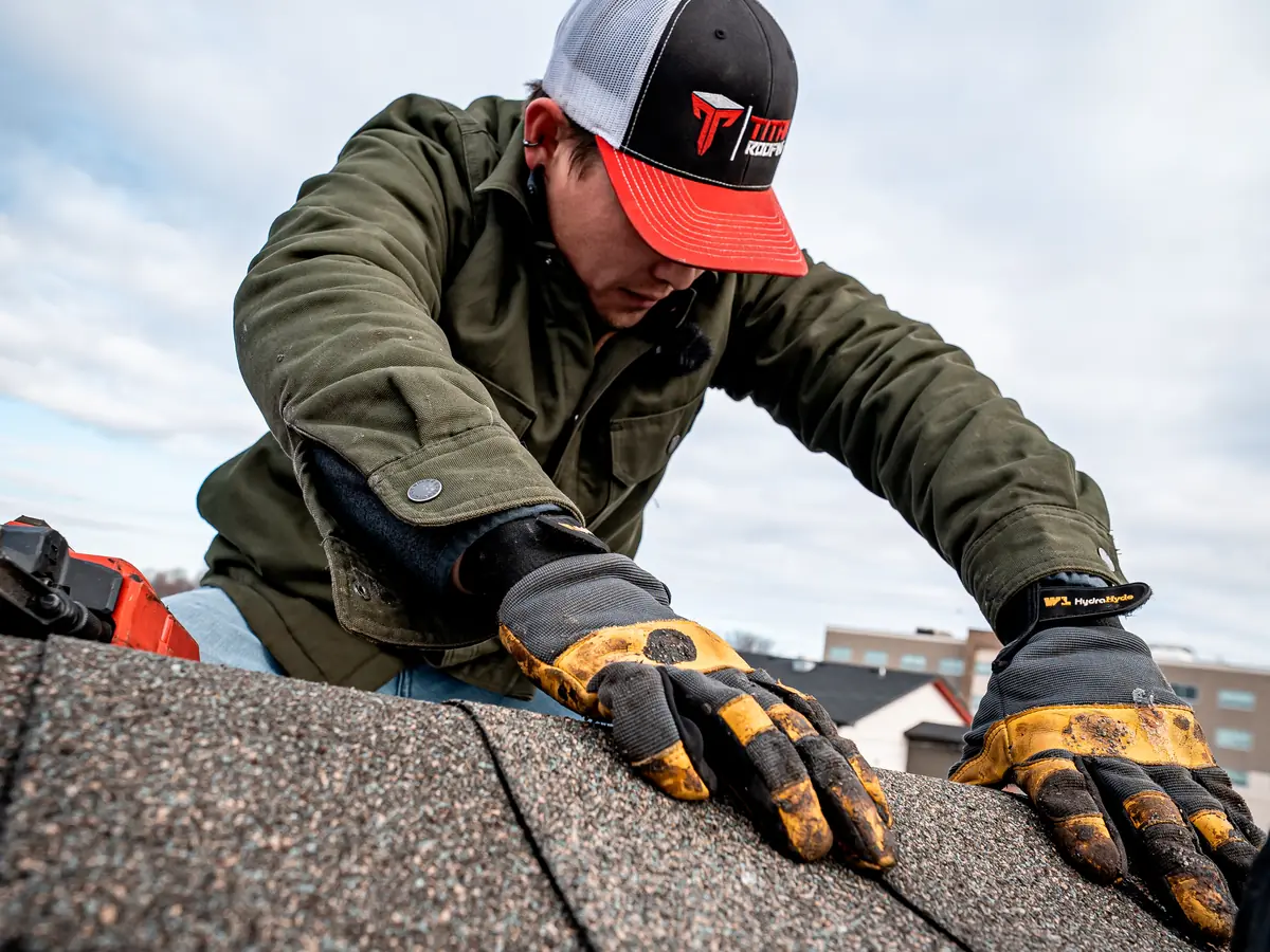 Roofer pressing a ridge cap shingle into place