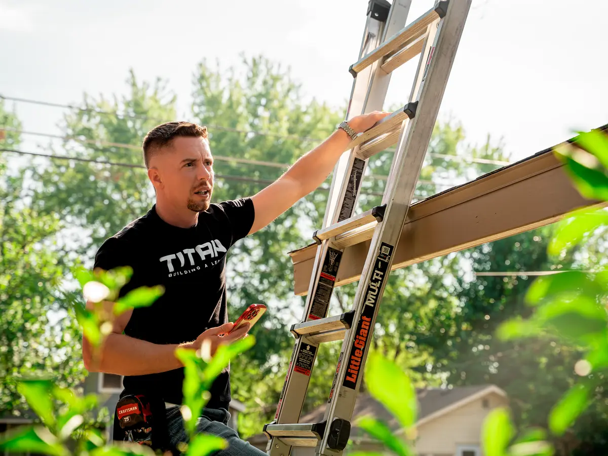Titan Roofing inspector setting a ladder against a home before a roof inspection