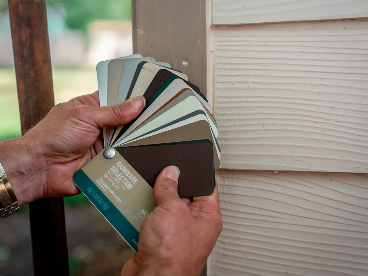 Siding color samples held up against a home's existing siding