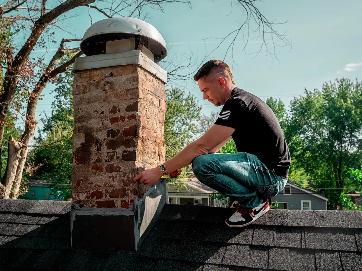 Titan Roofing inspector checking the flashing around a brick chimney