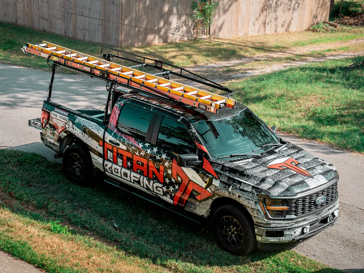 Titan Roofing's wrapped truck with ladders on the rack, parked on a Springfield street