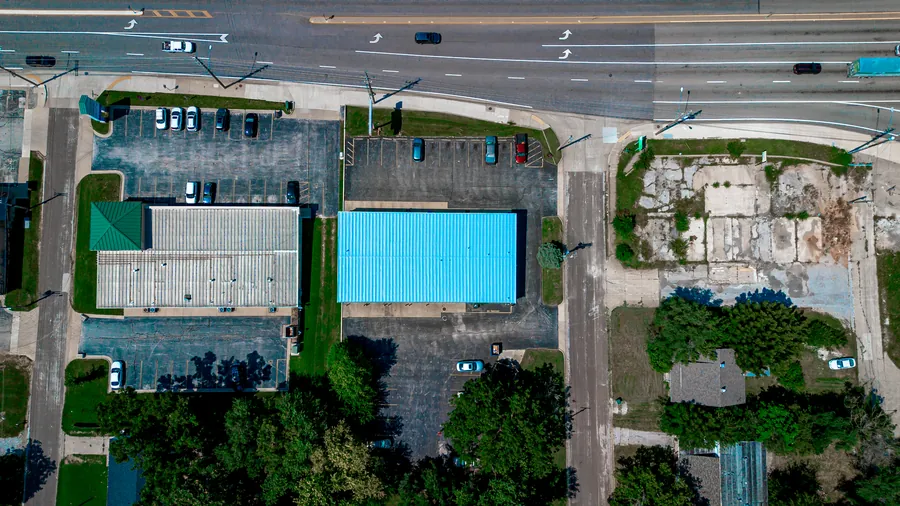 Blue coated commercial roof beside a busy street, seen from above