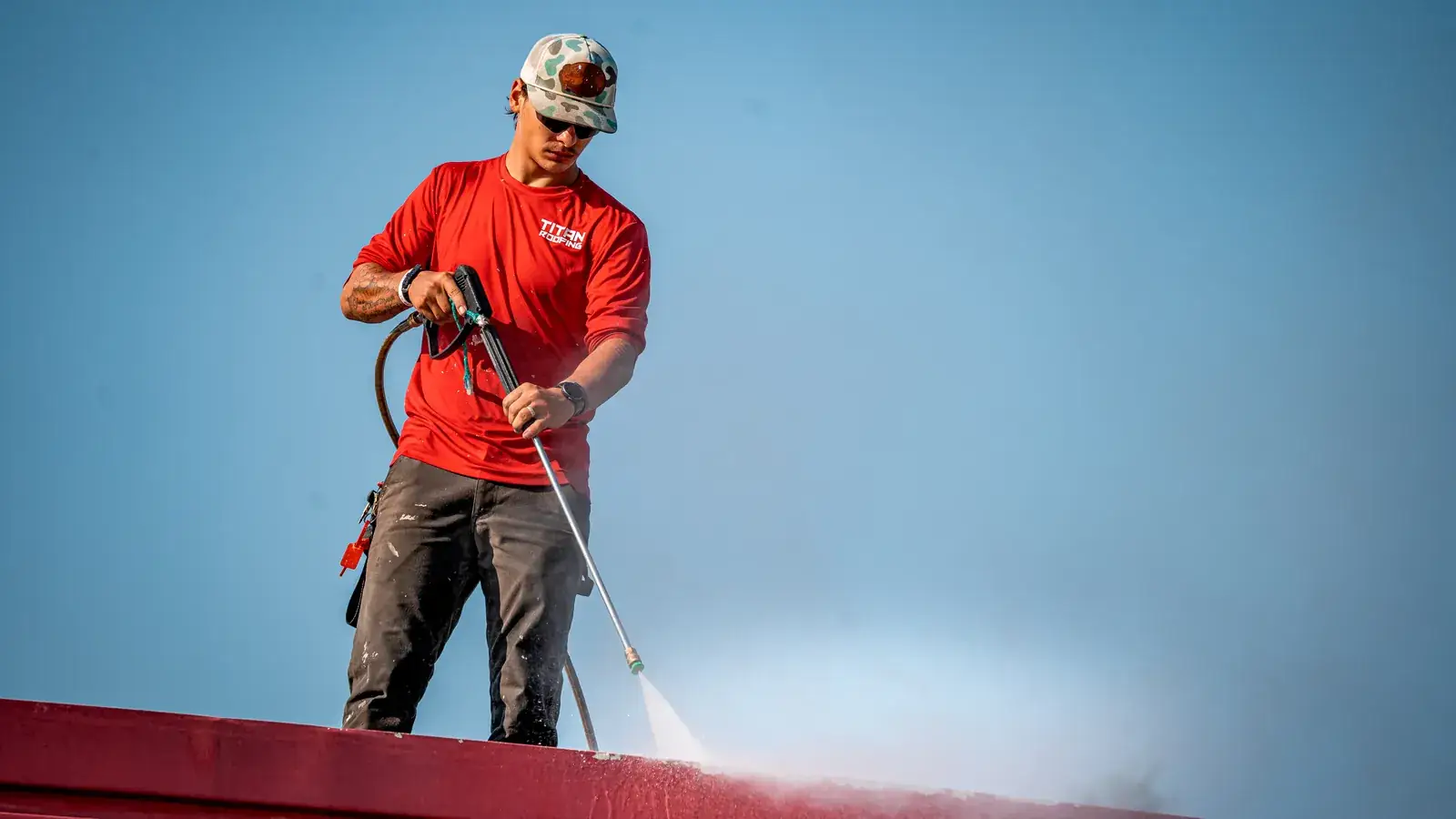 Titan crew member pressure washing a commercial roof before coating