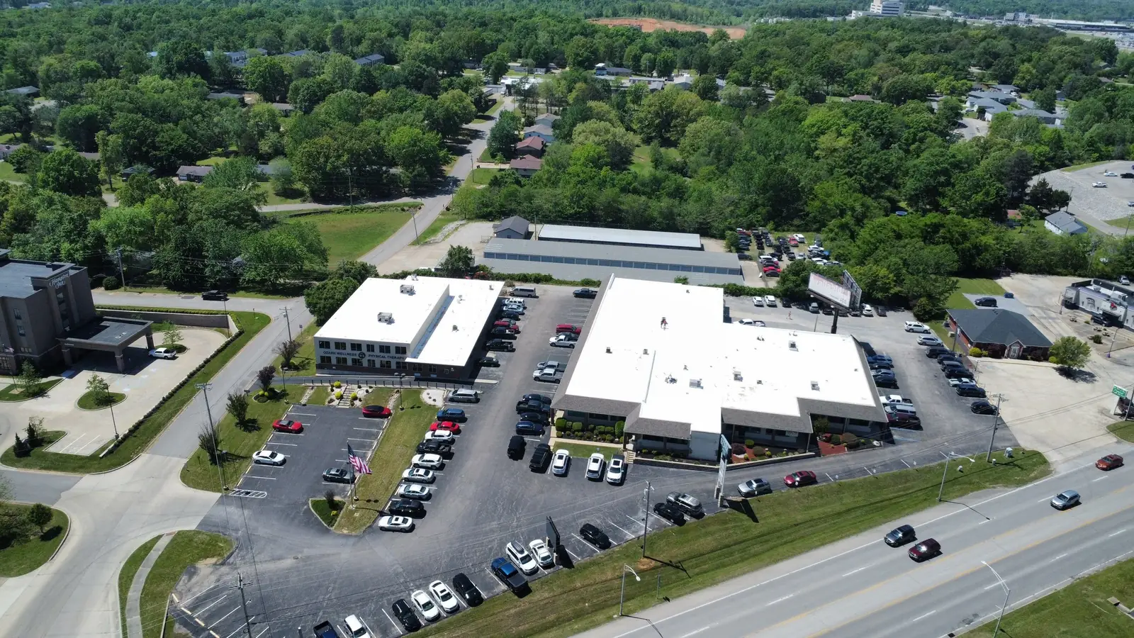 Business complex with new white roofs and a full parking lot, seen from above