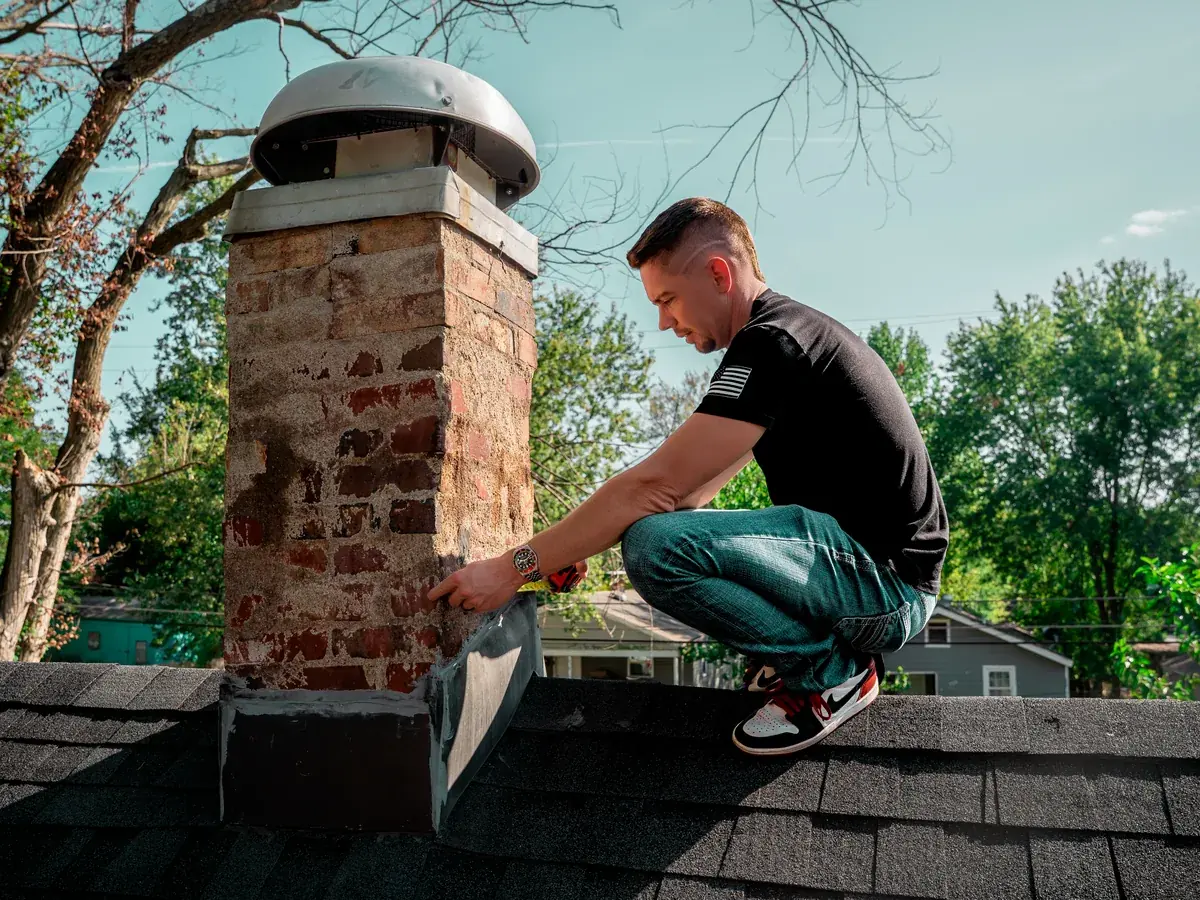 Titan Roofing inspector checking the flashing at the base of a brick chimney