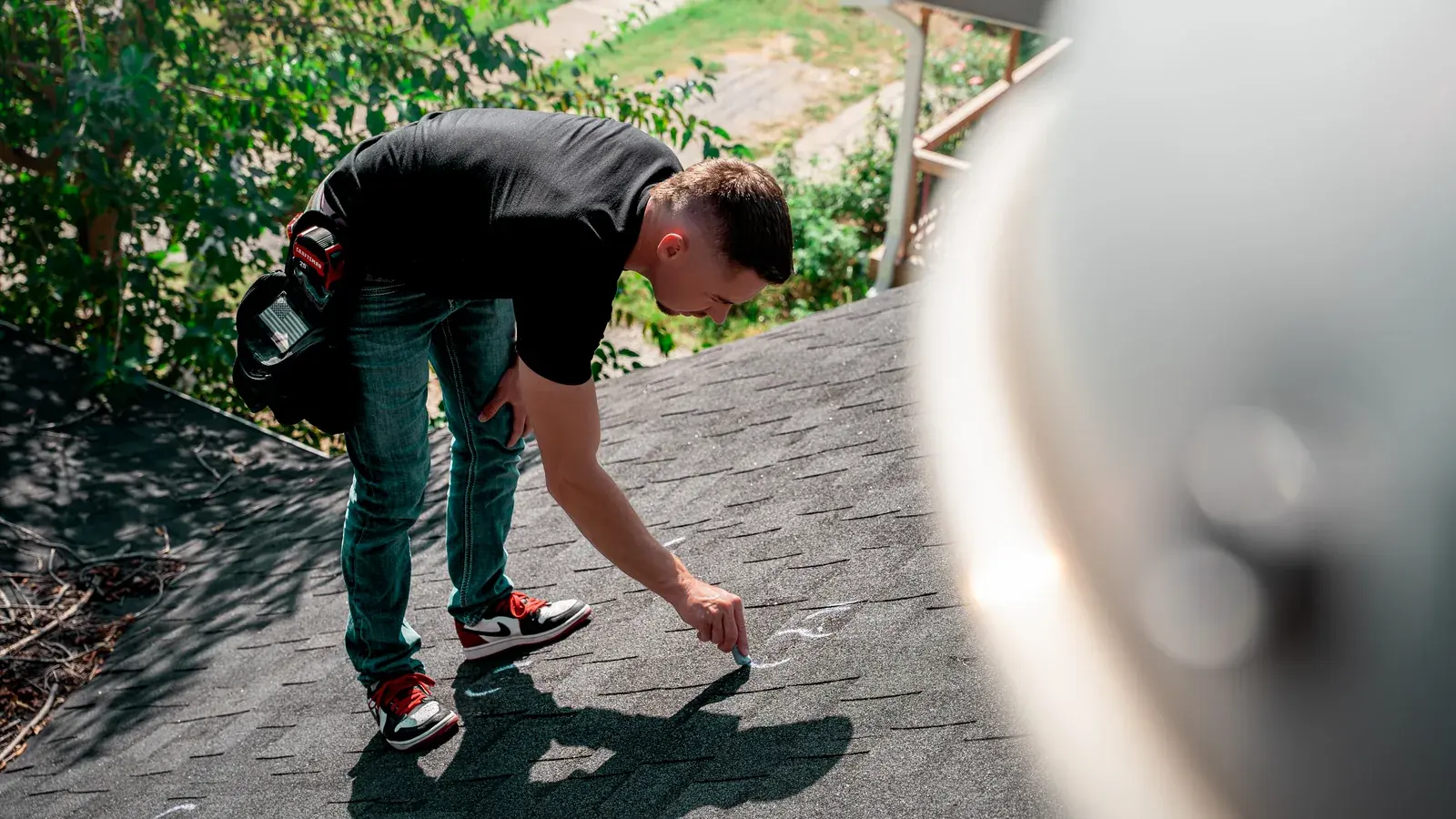 Titan inspector marking damaged shingles with chalk during a roof inspection
