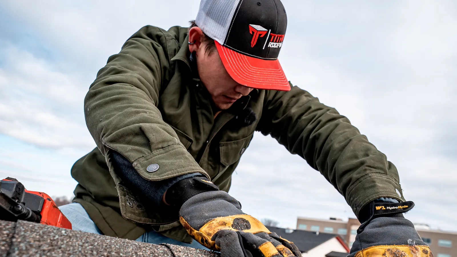 Titan roofer installing ridge cap shingles, seen from above
