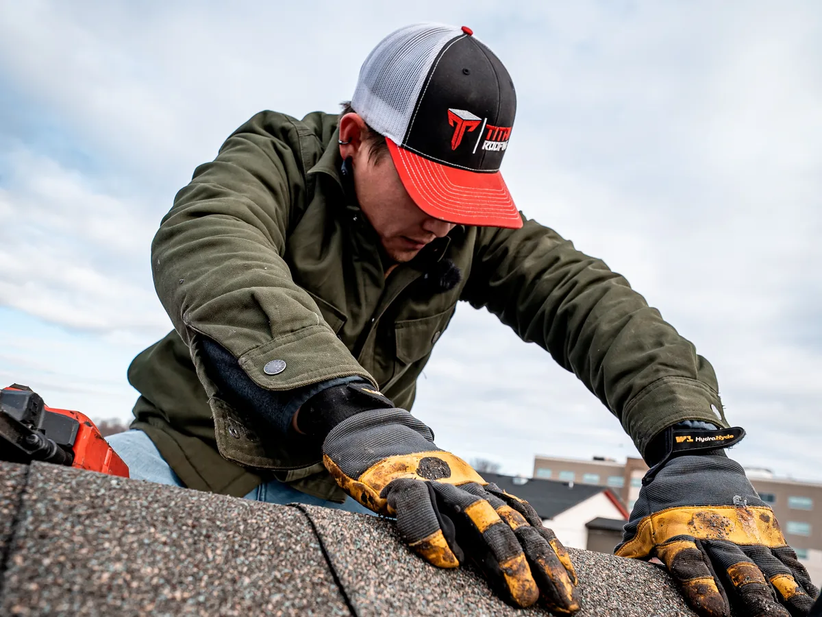 Titan Roofing crew member in a Titan cap pressing ridge cap shingles into place