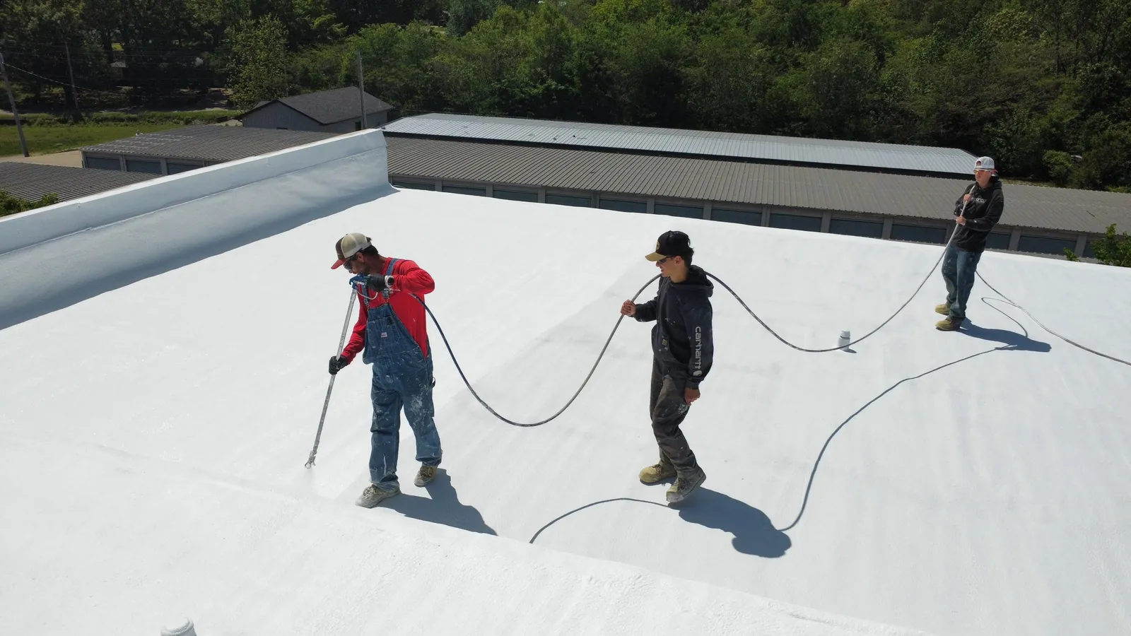 Titan spray foam crew running hoses across a flat commercial roof