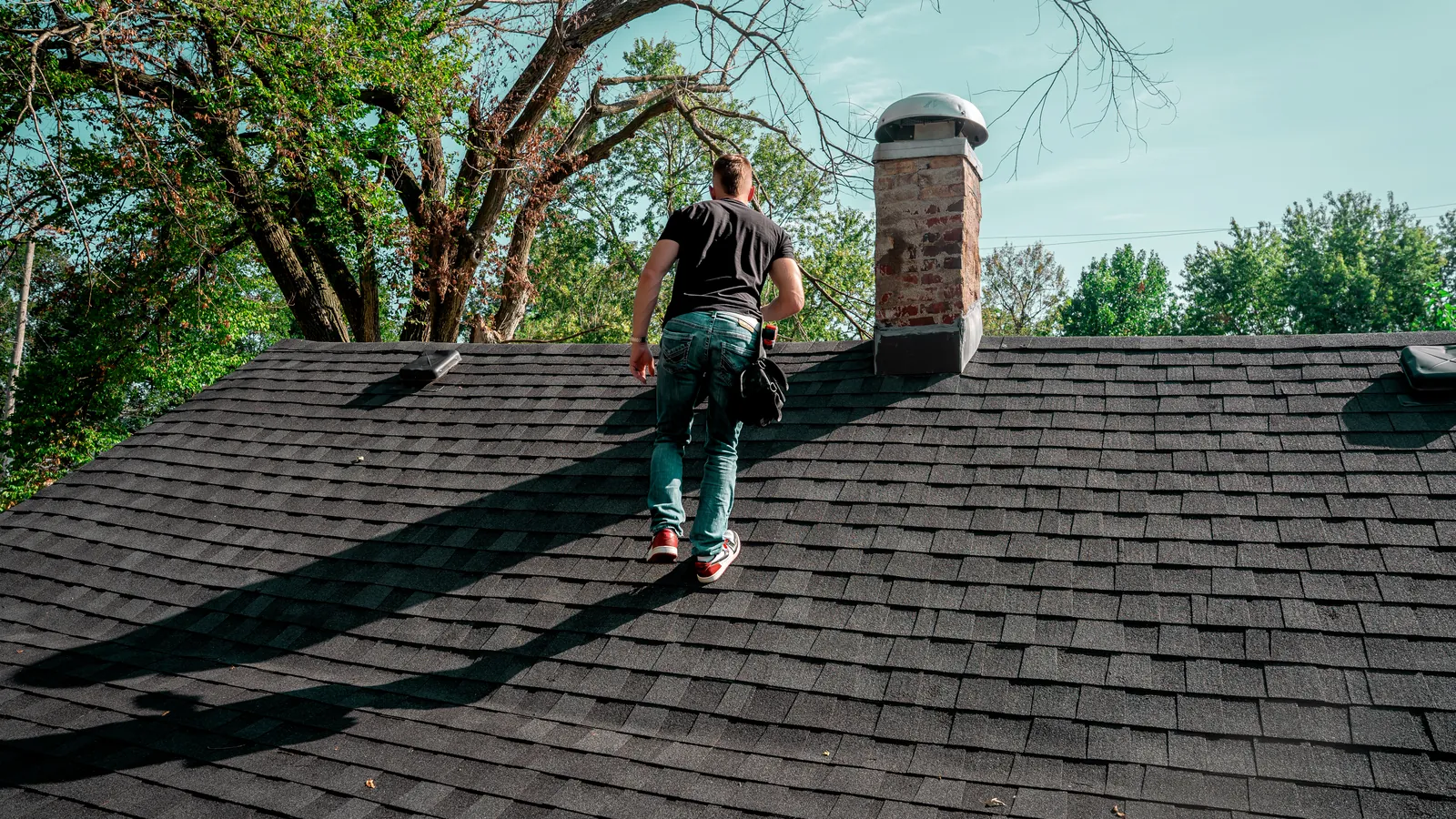 Titan inspector walking a shingle roof toward the chimney during a storm inspection
