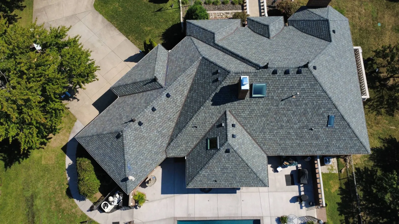 Drone view of a large Missouri home with a new gray synthetic slate roof installed by Titan Roofing