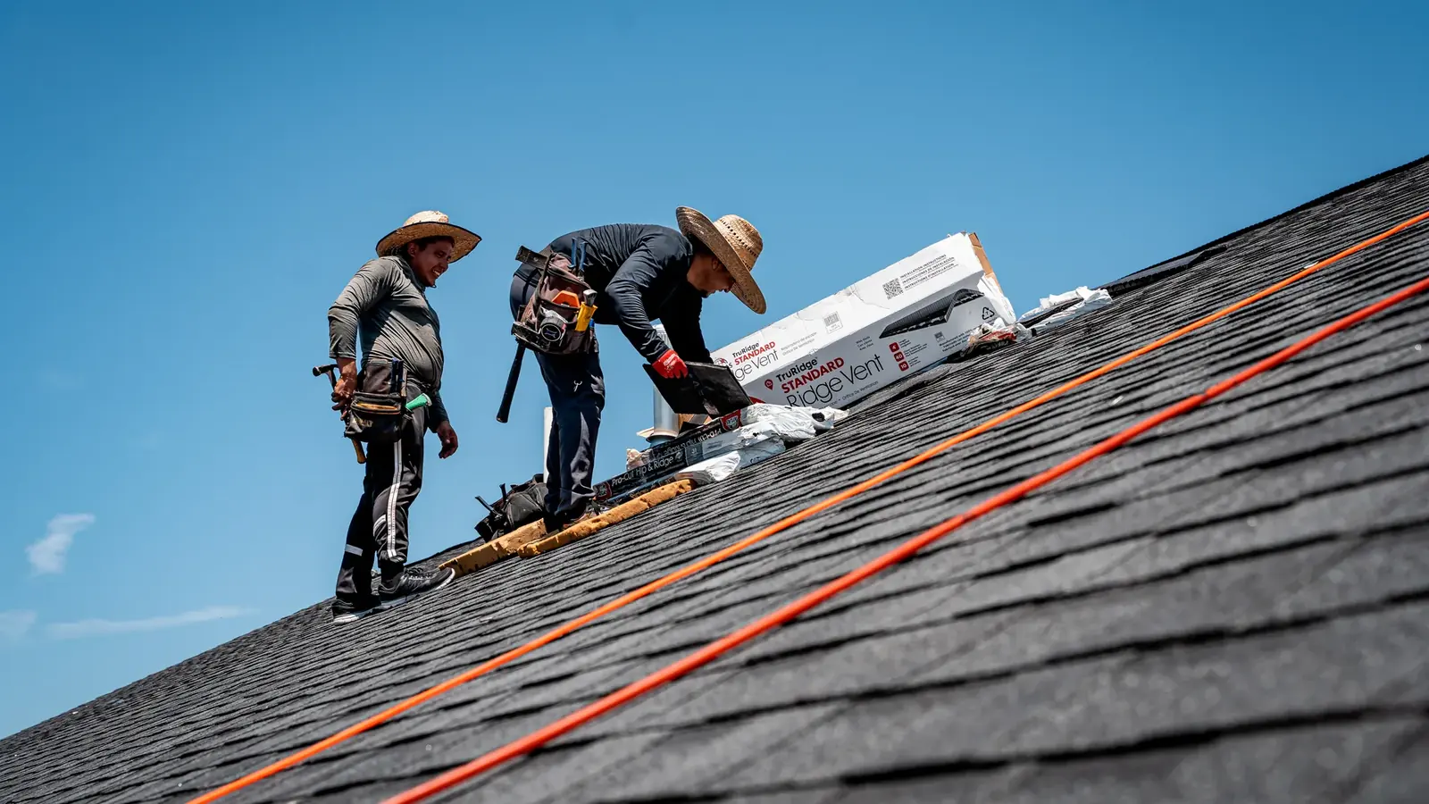 Titan roofers installing shingles against a blue sky