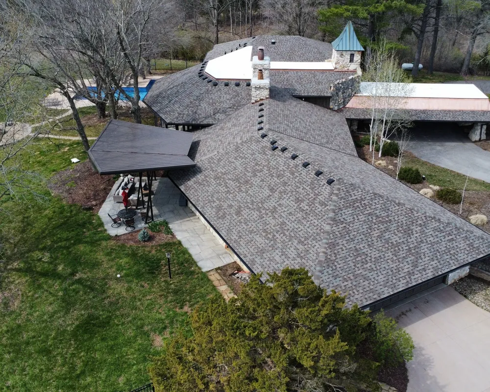 Large hillside home with a turret and a new architectural shingle roof