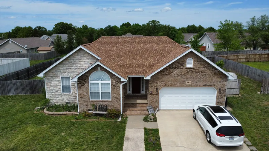 Stone ranch home with new white gutters and downspouts